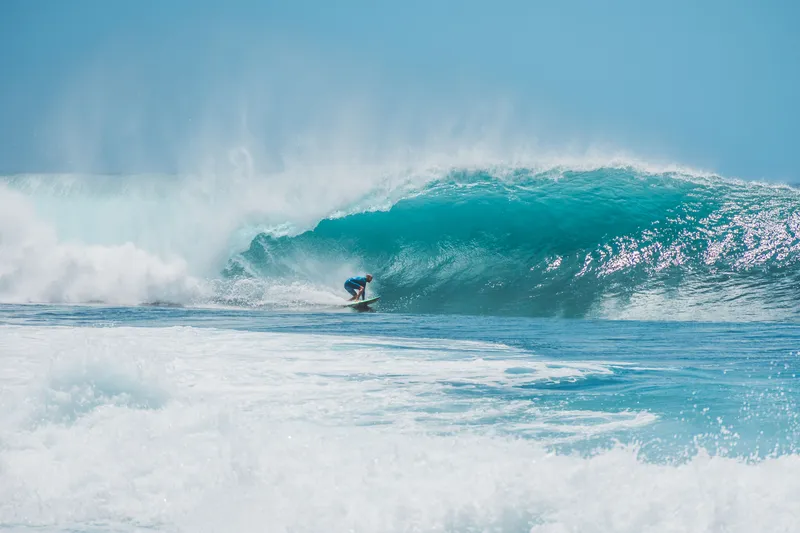 Surfer set against a wide blue wave